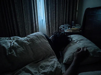 A dark bedroom at night with someone lying awake in bed